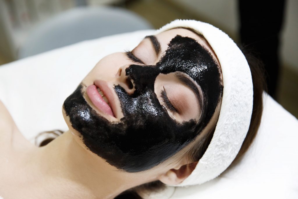 Girl with black mask lies on the table in spa saloon